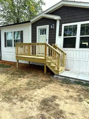 Front entry deck with wooden railing and stairs attached to a two-tone house in Murray KY