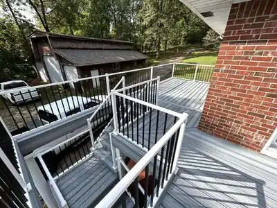 Newly built gray deck with white rails and black balusters beside a brick house in Murray, KY