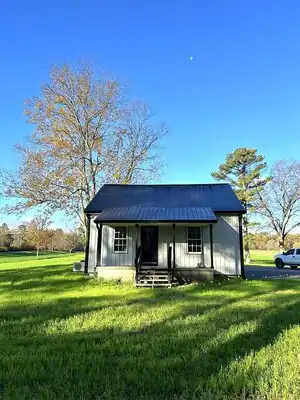 Tiny house cottage with metal roof and front porch on a grassy lot in Murray KY