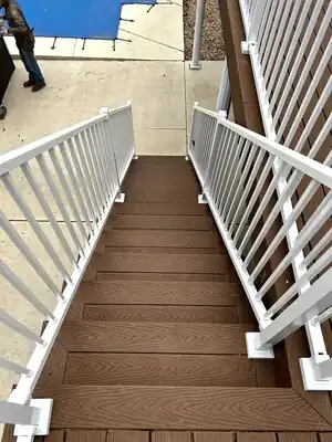 Outdoor brown deck and stairs with white railings leading to a concrete patio in Kentucky