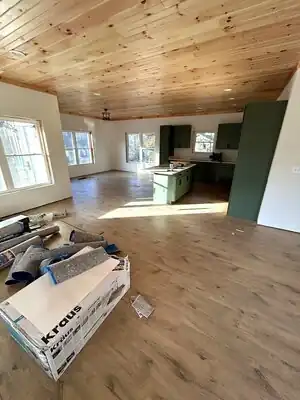 Interior of a new home under construction in Murray KY with green kitchen cabinets and island, wooden ceiling, and large windows.