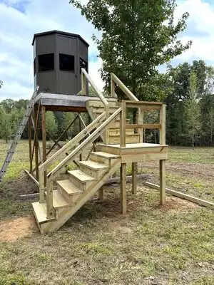 Unfinished elevated wooden playhouse with stairs and railing on stilts in a rural Kentucky field